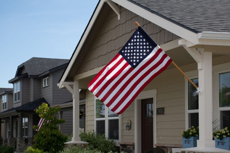 A stylish suburban house with a vibrant American flag displayed outside in daylight.