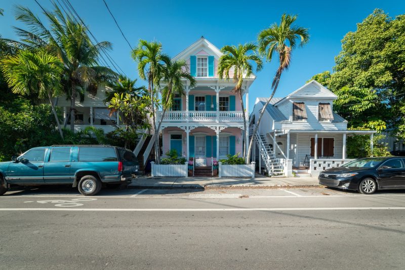 Home 28 Colorful historic houses surrounded by palm trees on a sunny street in Key West, Florida.